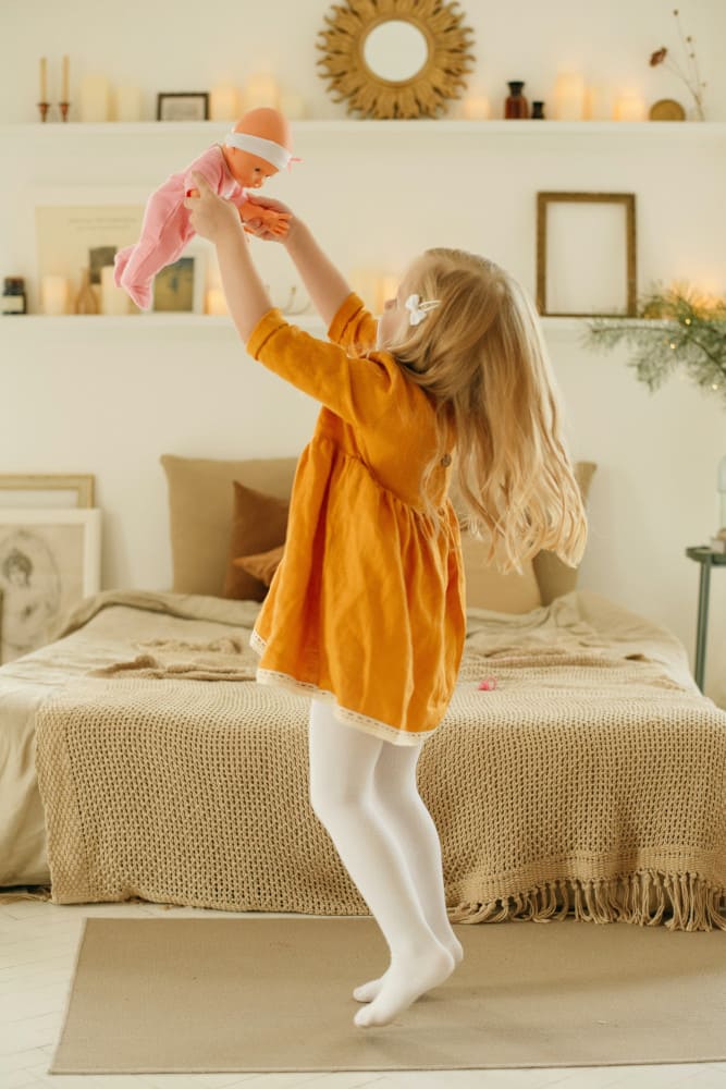 Une petite fille joue avec sa poupée au milieu de sa chambre